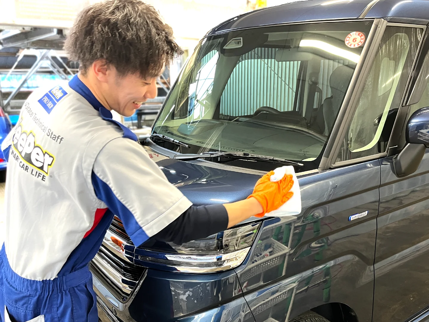 車のボンネットを丁寧に拭き上げる足立千住店の施工スタッフ